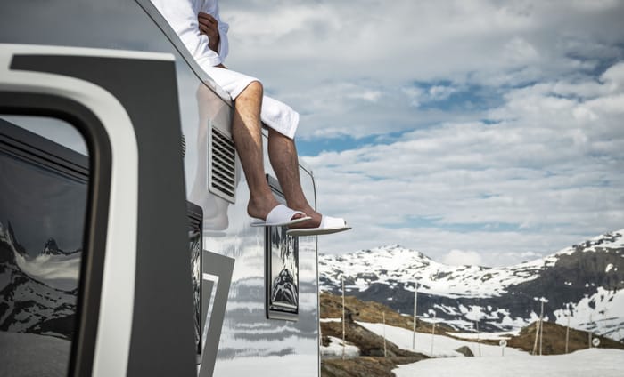 man relaxing on top of his Brinkley RV in the mountains living a luxury rv lifestyle